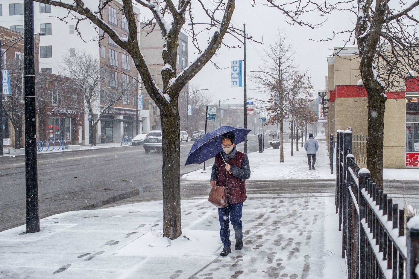 A pedestrian used an umbrella along North Broadway as a wintry mix falls in the Edgewater neighborhood, March 15, 2021.